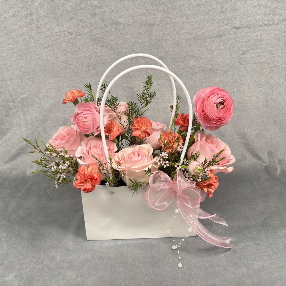 pink roses and orange carnations with waxflowers in gift bag