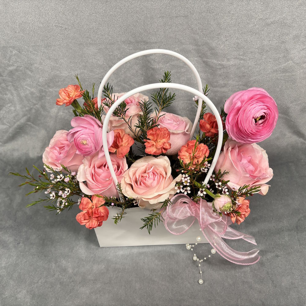 pink roses and orange carnations with waxflowers in gift bag